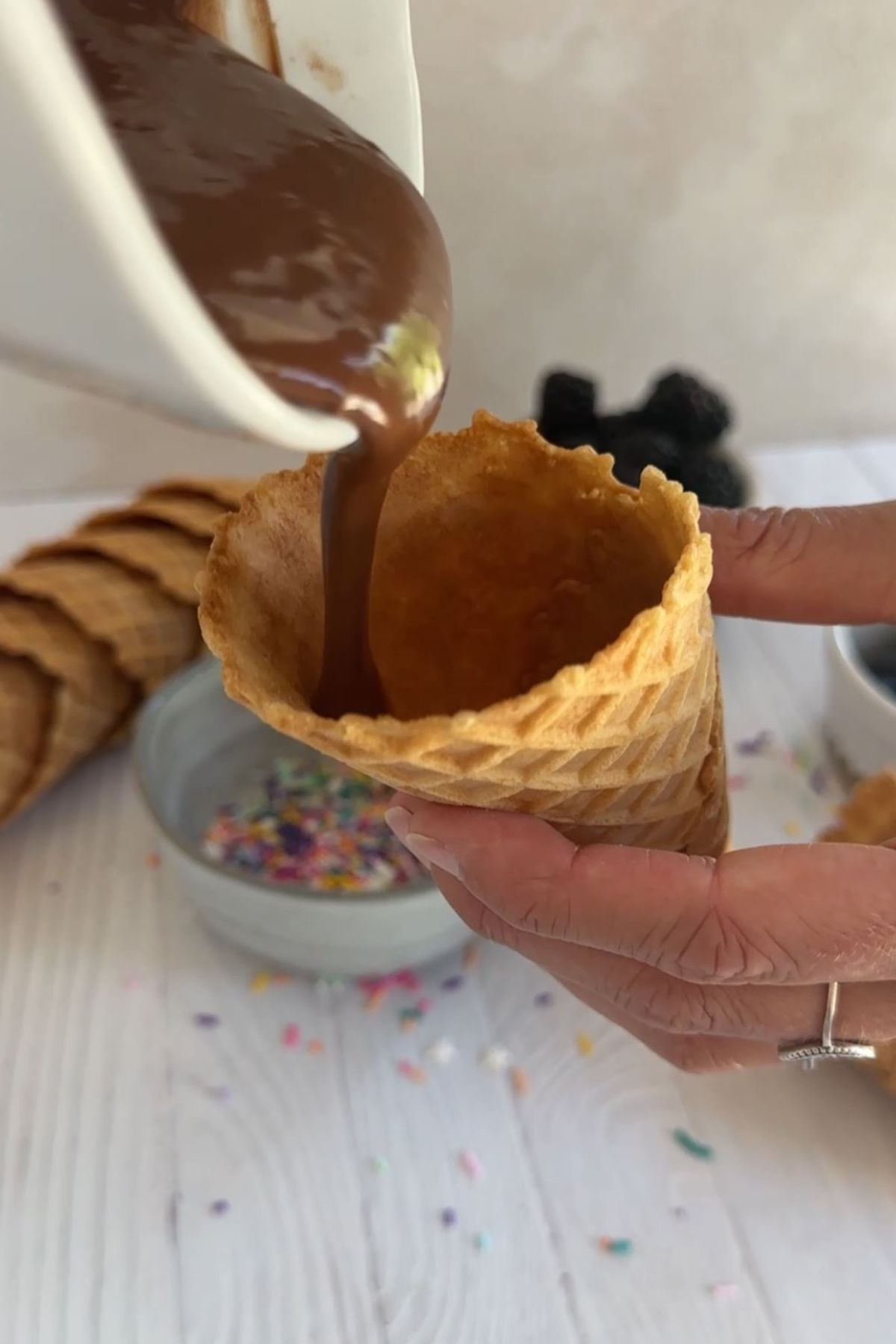 Melted chocolate being poured into an ice cream cone.
