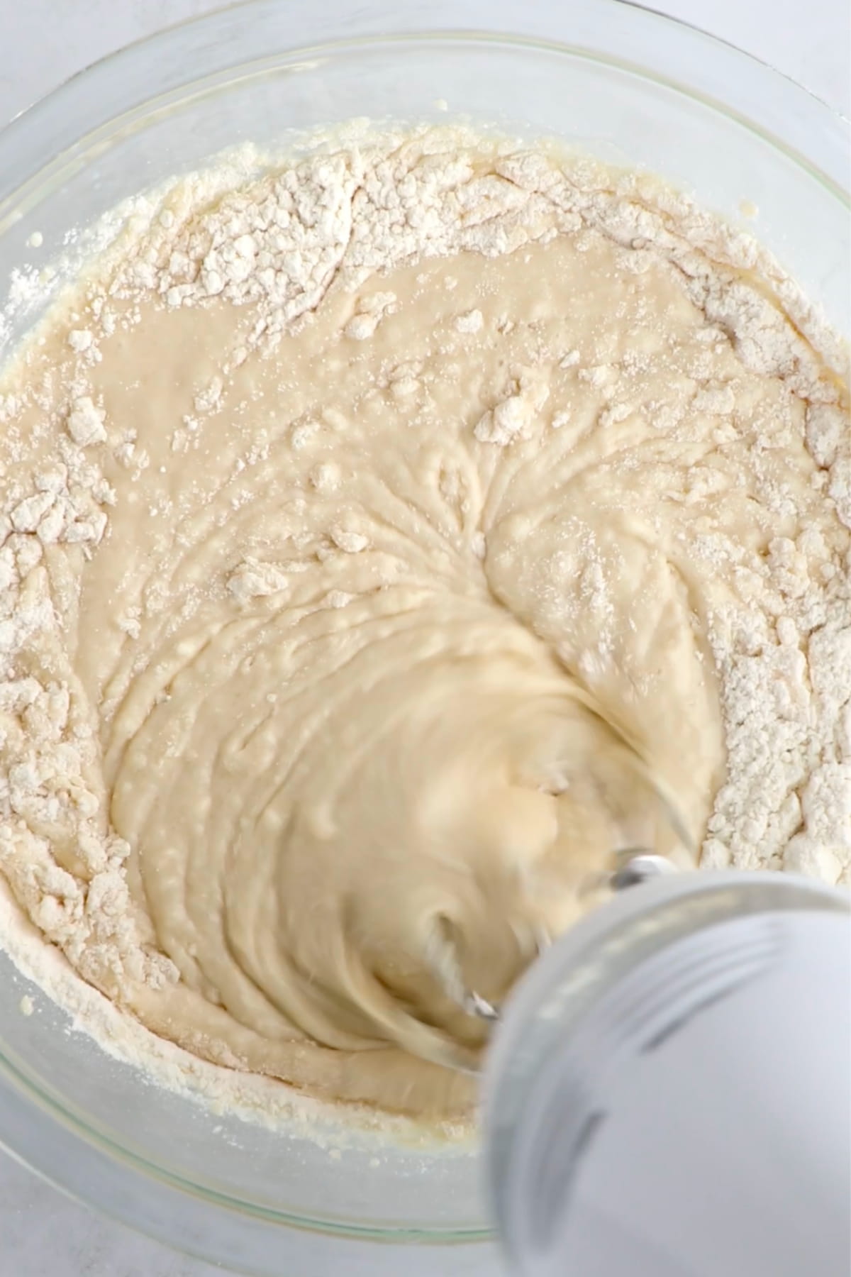 The vegan cake batter being mixed in a bowl with an electric hand mixer.