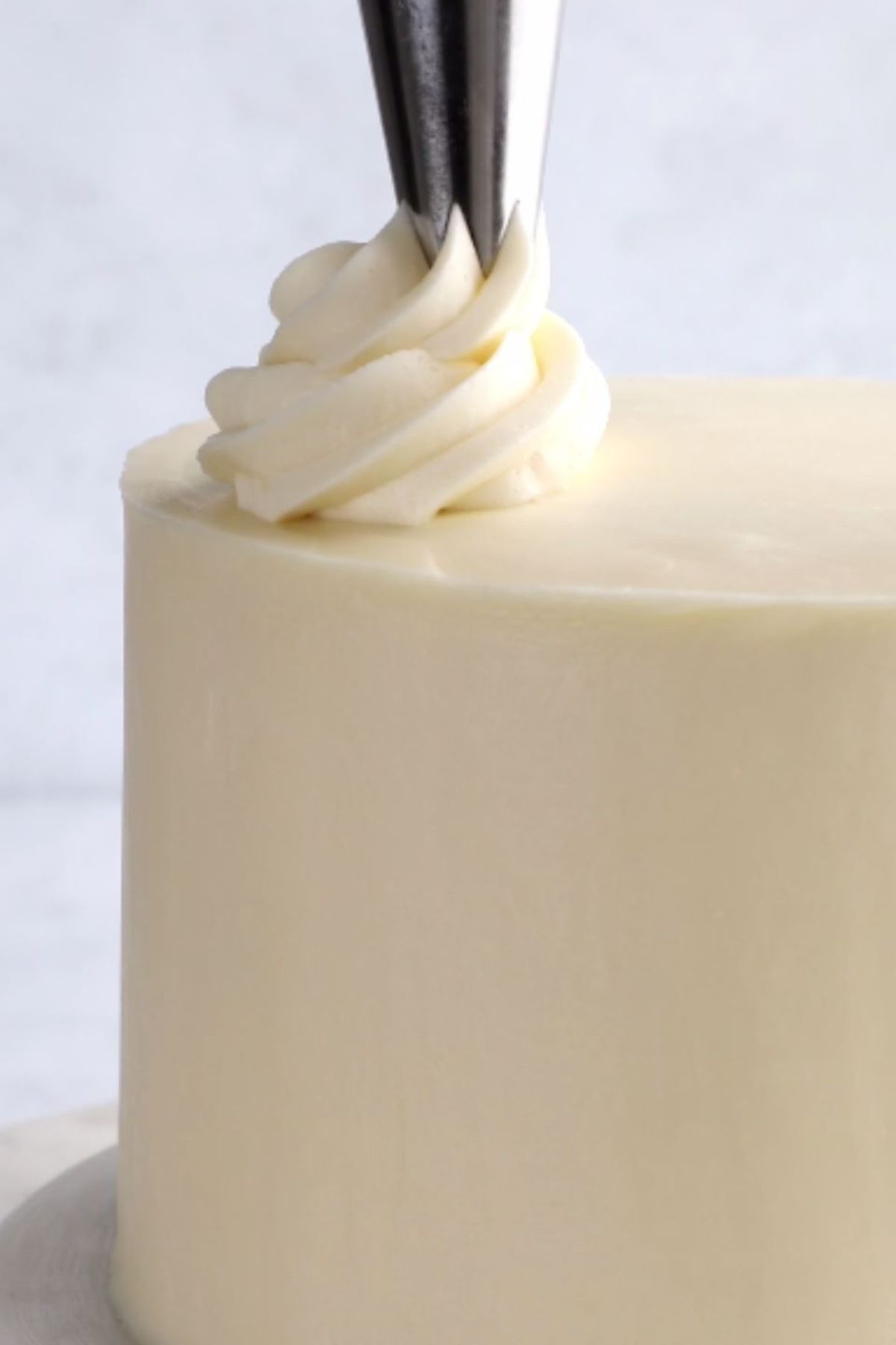 Piped swirl of vegan frosting on top of a layered birthday cake.