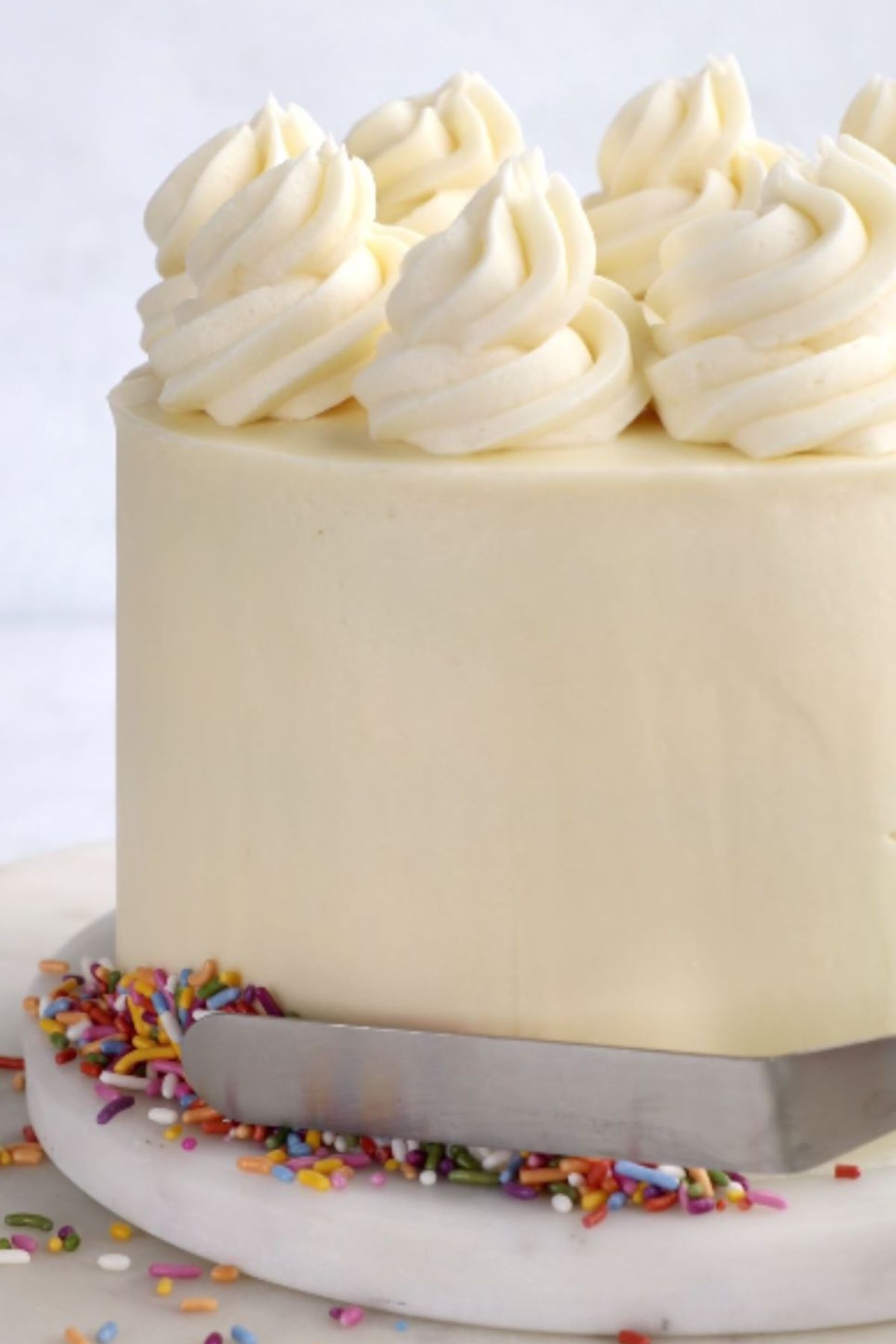 A vegan birthday sprinkle cake being decorated.