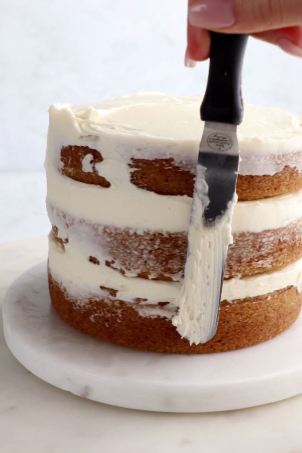 Icing being applied to a three-layer vegan cake.