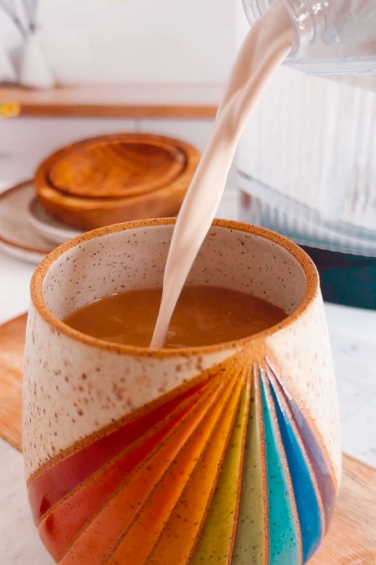 Pouring vegan coffee creamer into a mug filled with coffee.