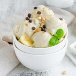 A bowl full of scoops of vegan gelato with dairy-free chocolate chips and peanuts on top.