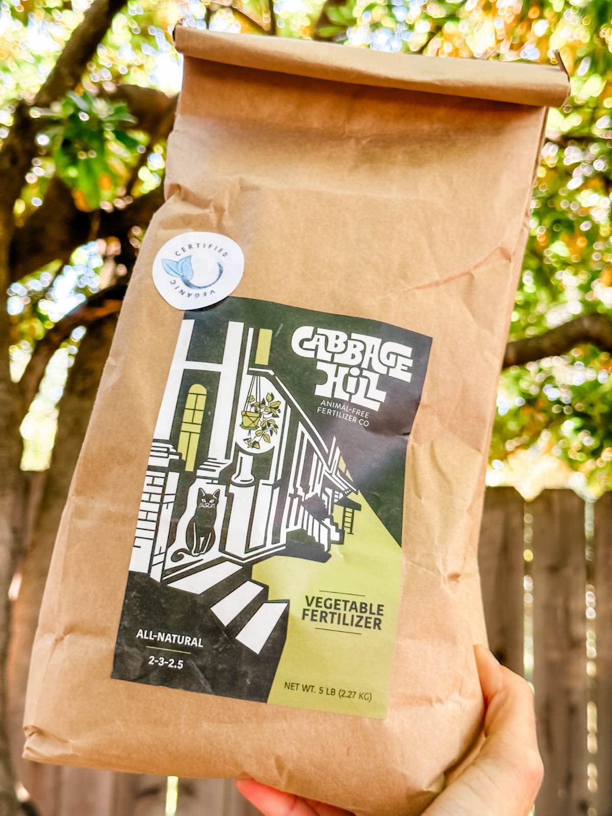 Vegan woman holding out a bag of Cabbage Hill veganic vegetable fertilizer. 