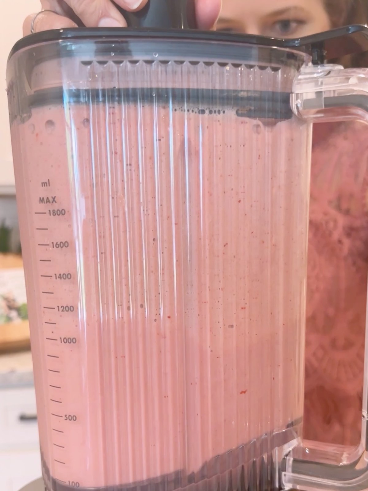A blender with a pink strawberry banana mixture to use for the strawberry popsicles. 