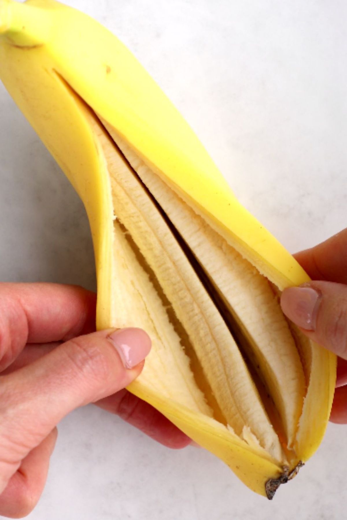 A banana sliced lengthwise pulled open to reveal the interior.