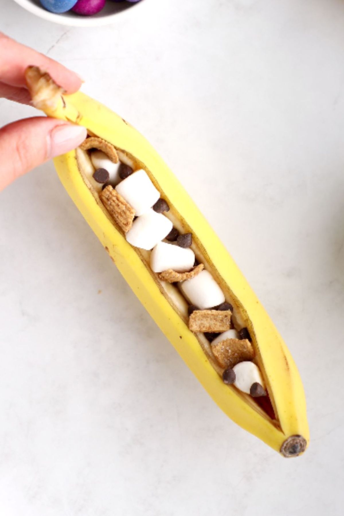 A campfire banana boat filled with vegan marshmallows and organic graham crunch crackers.