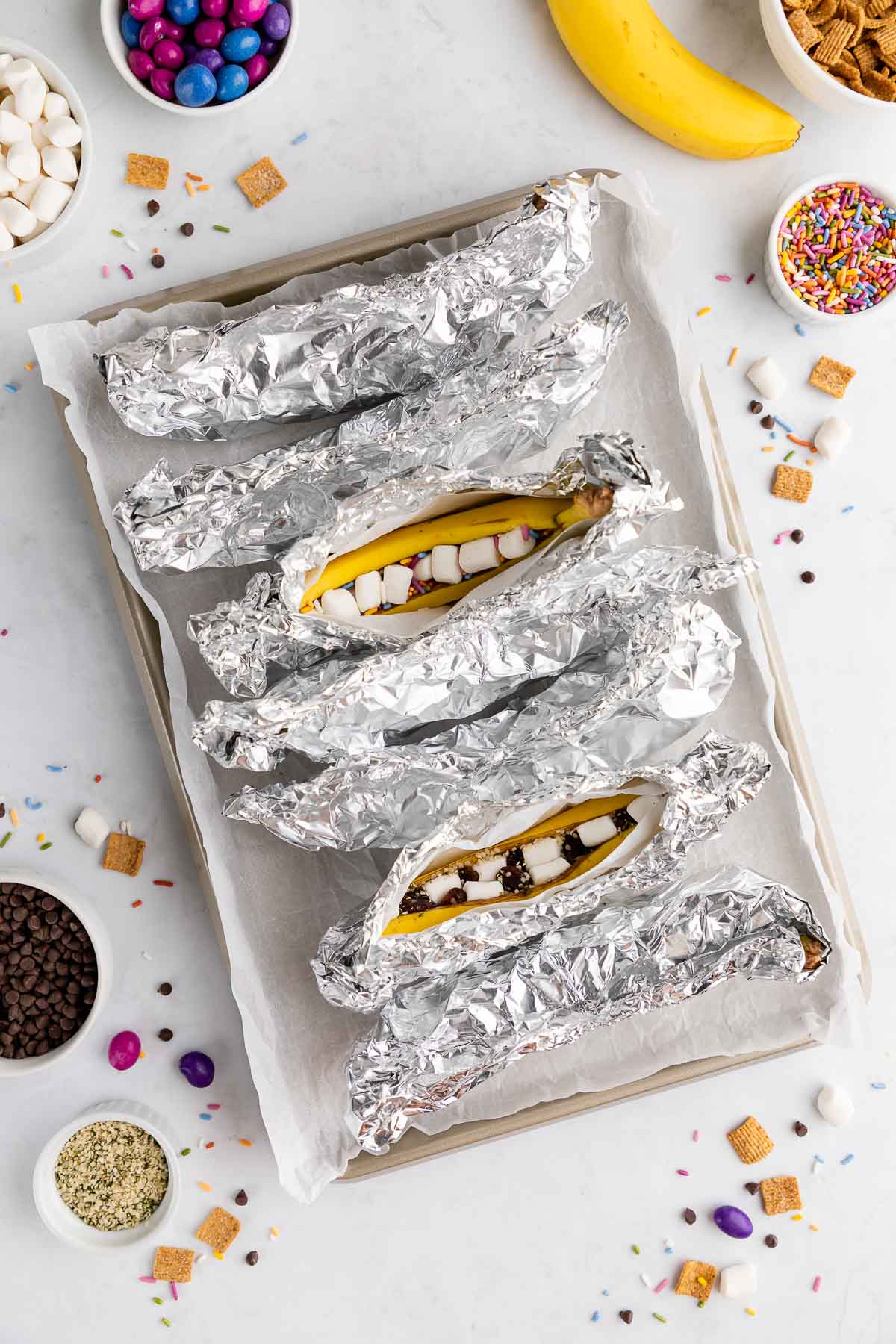Campfire banana boats, wrapped in foil and lined up.