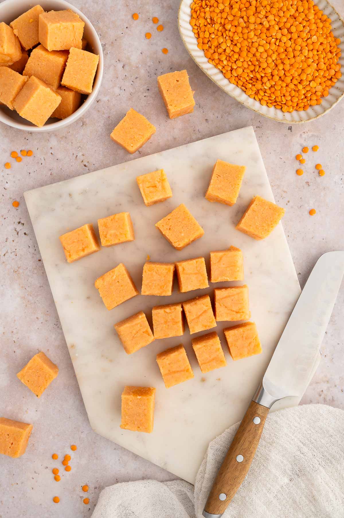 Red lentil tofu cubes on a tabletop.