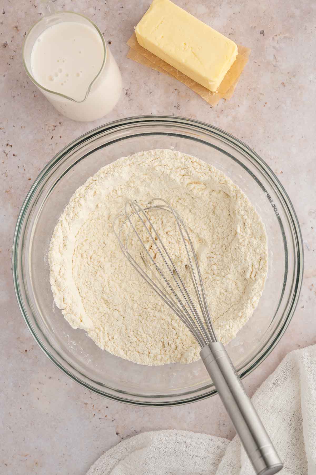 A bowl of flour with a whisk.