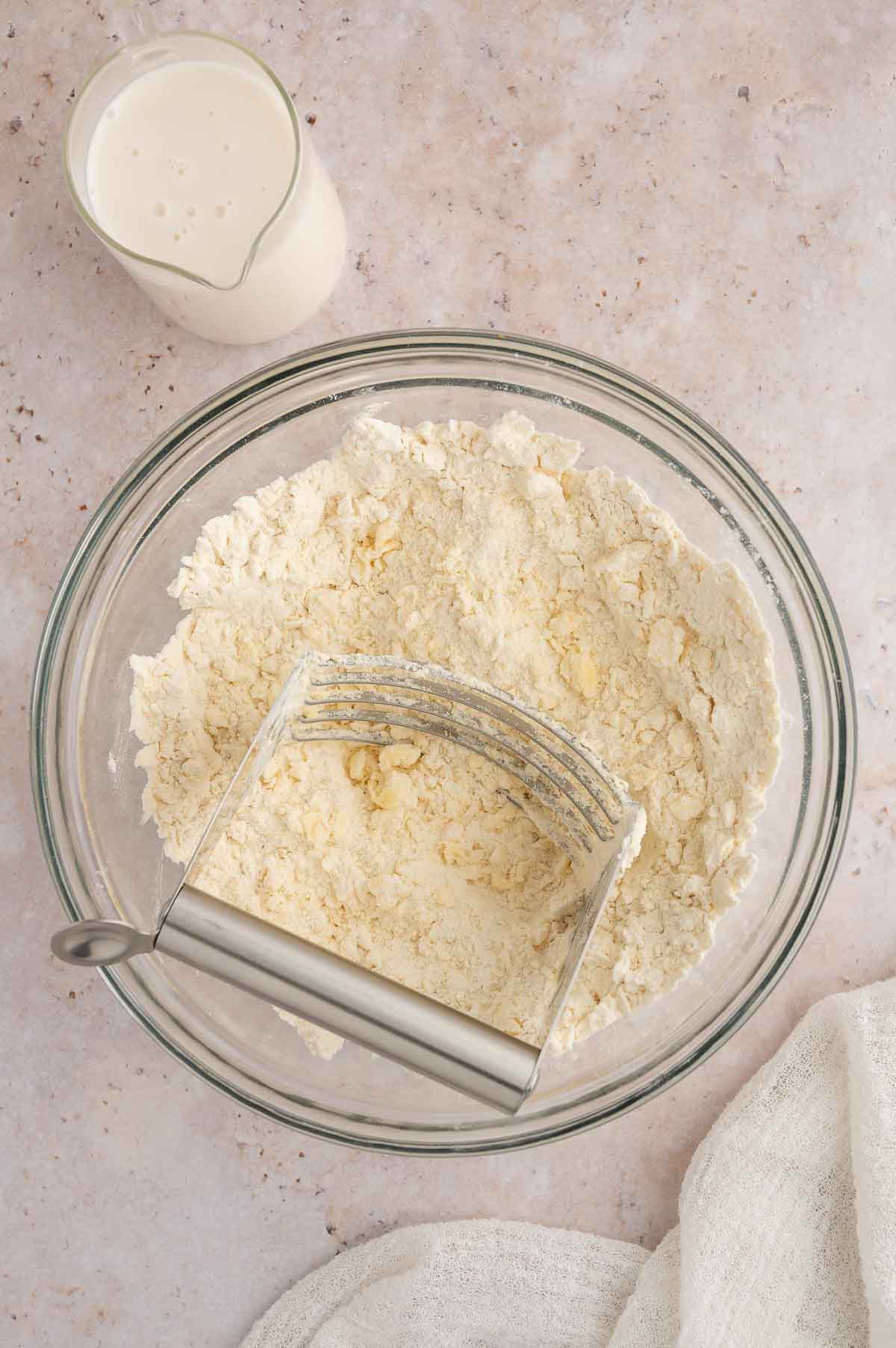 A bowl of flour with a biscuit cutter inside.