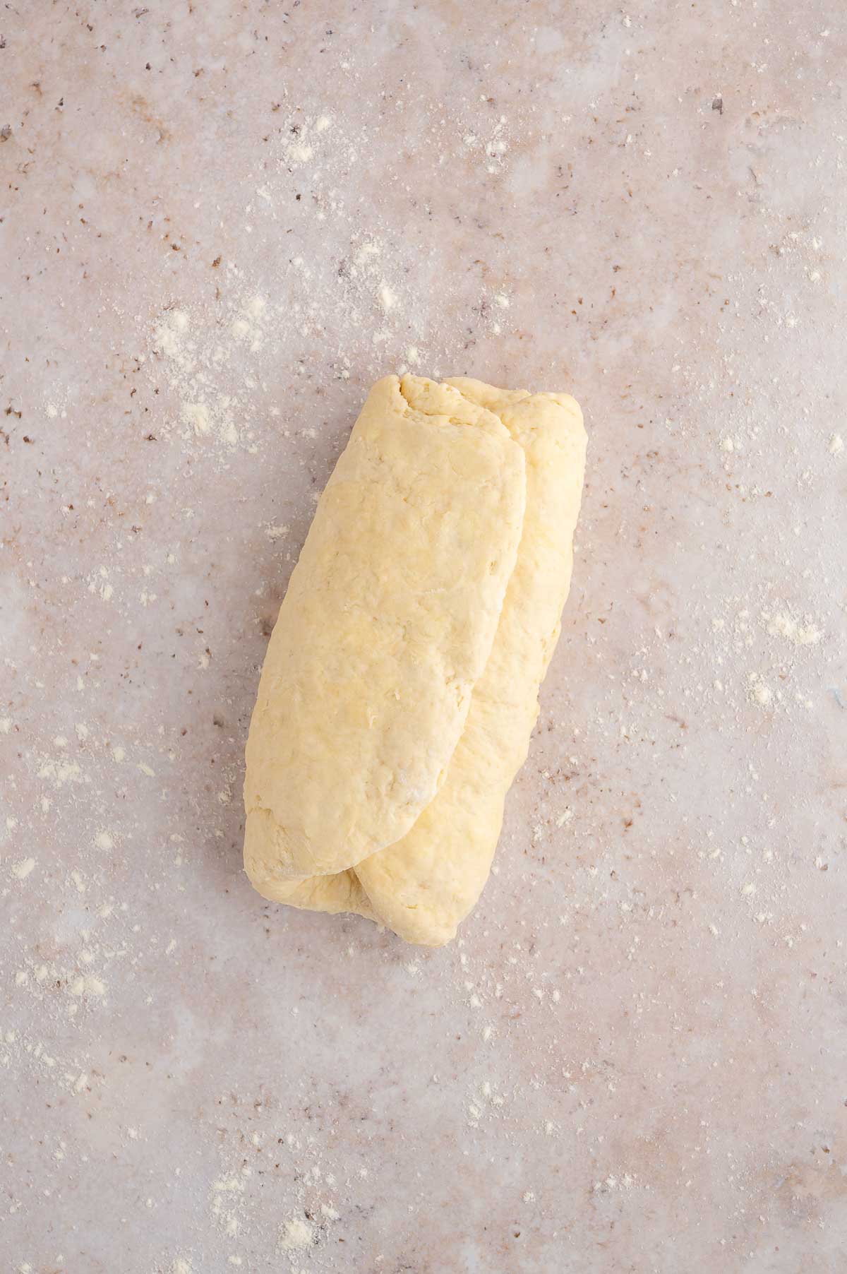Folded vegan biscuit dough on a countertop.
