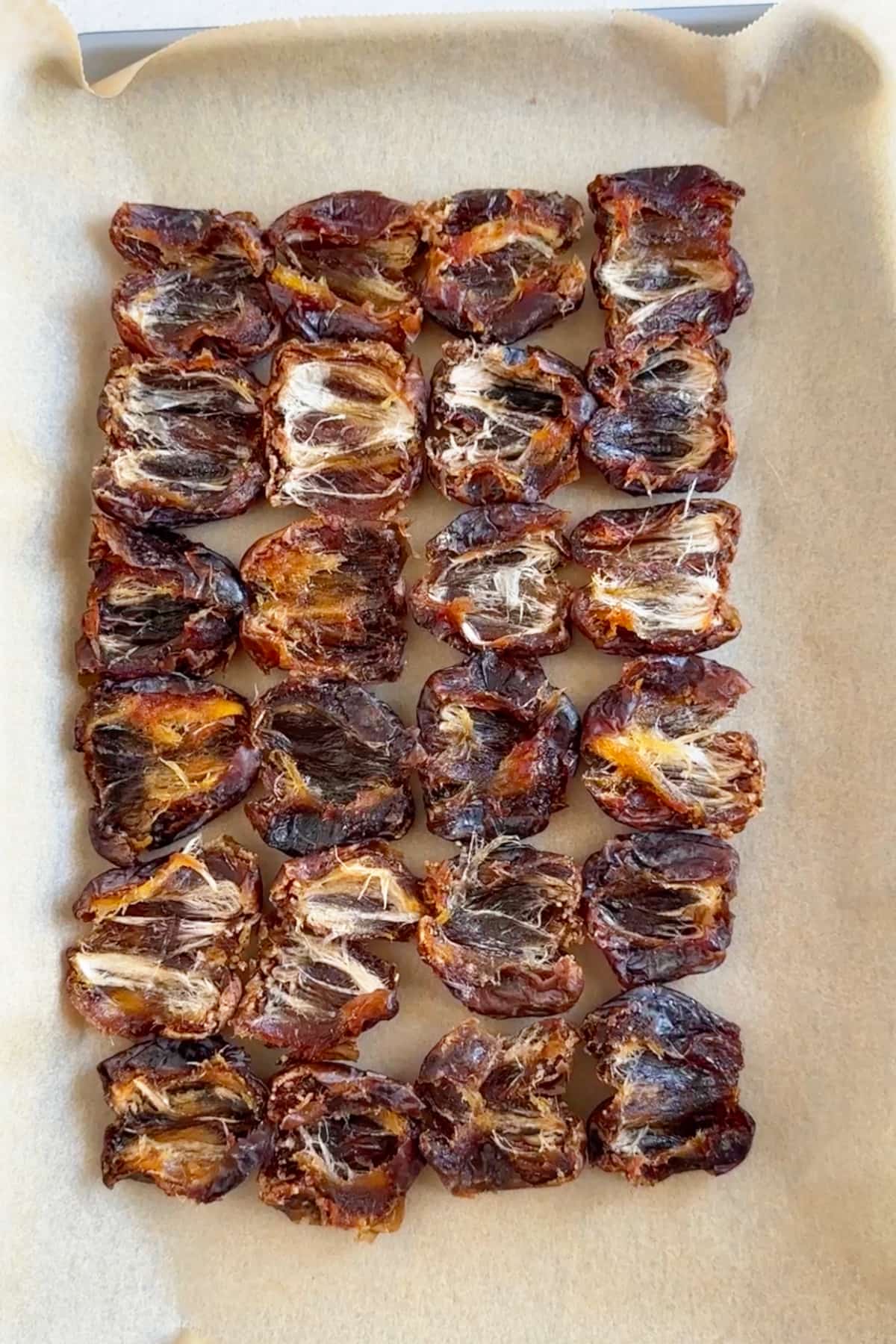 Dates placed on a baking tray lined with parchment paper in a single layer.