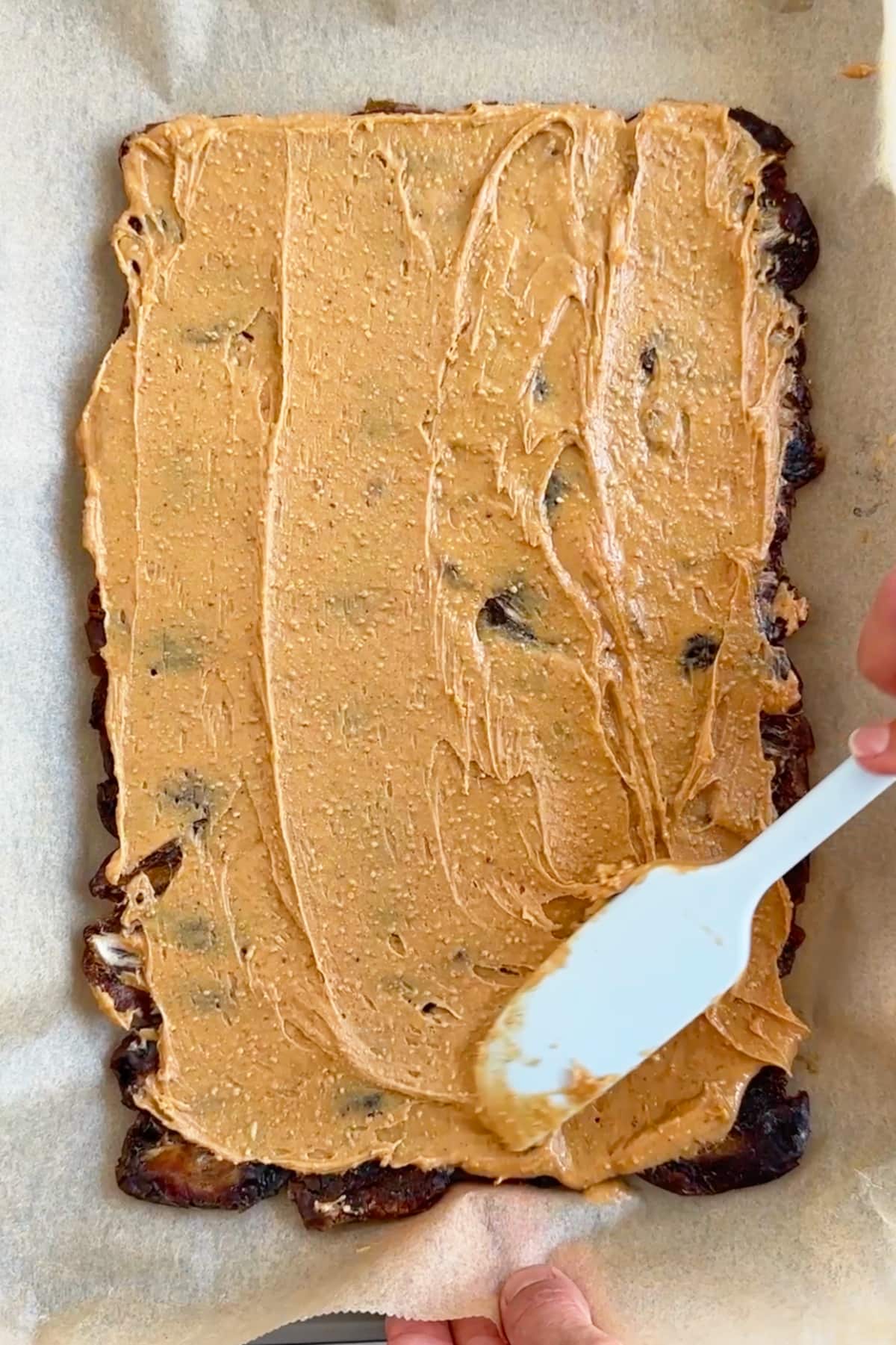 A layer of creamy peanut butter spread over the dates.