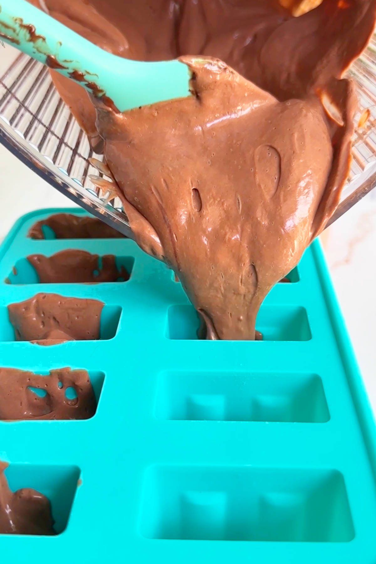 The fudgesicle mixture being poured from the blender pitcher into popsicle molds.