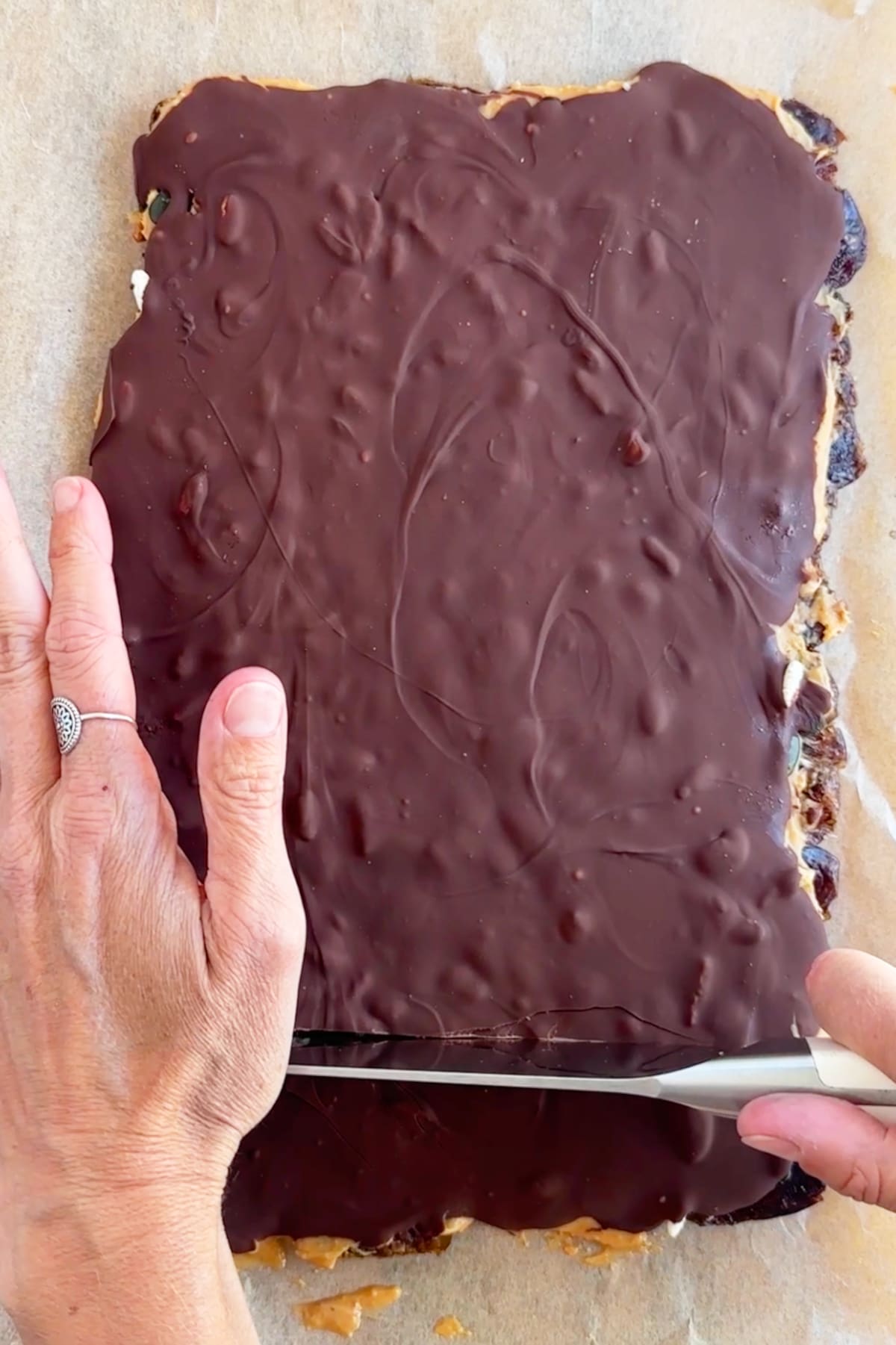 Hands slicing the frozen date bark with a sharp knife.