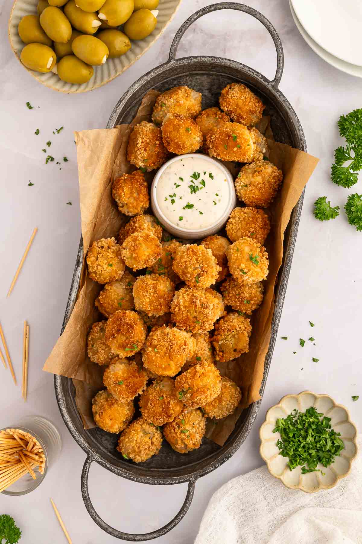 A serving tray of fried olives, served with a bowl of creamy dip.