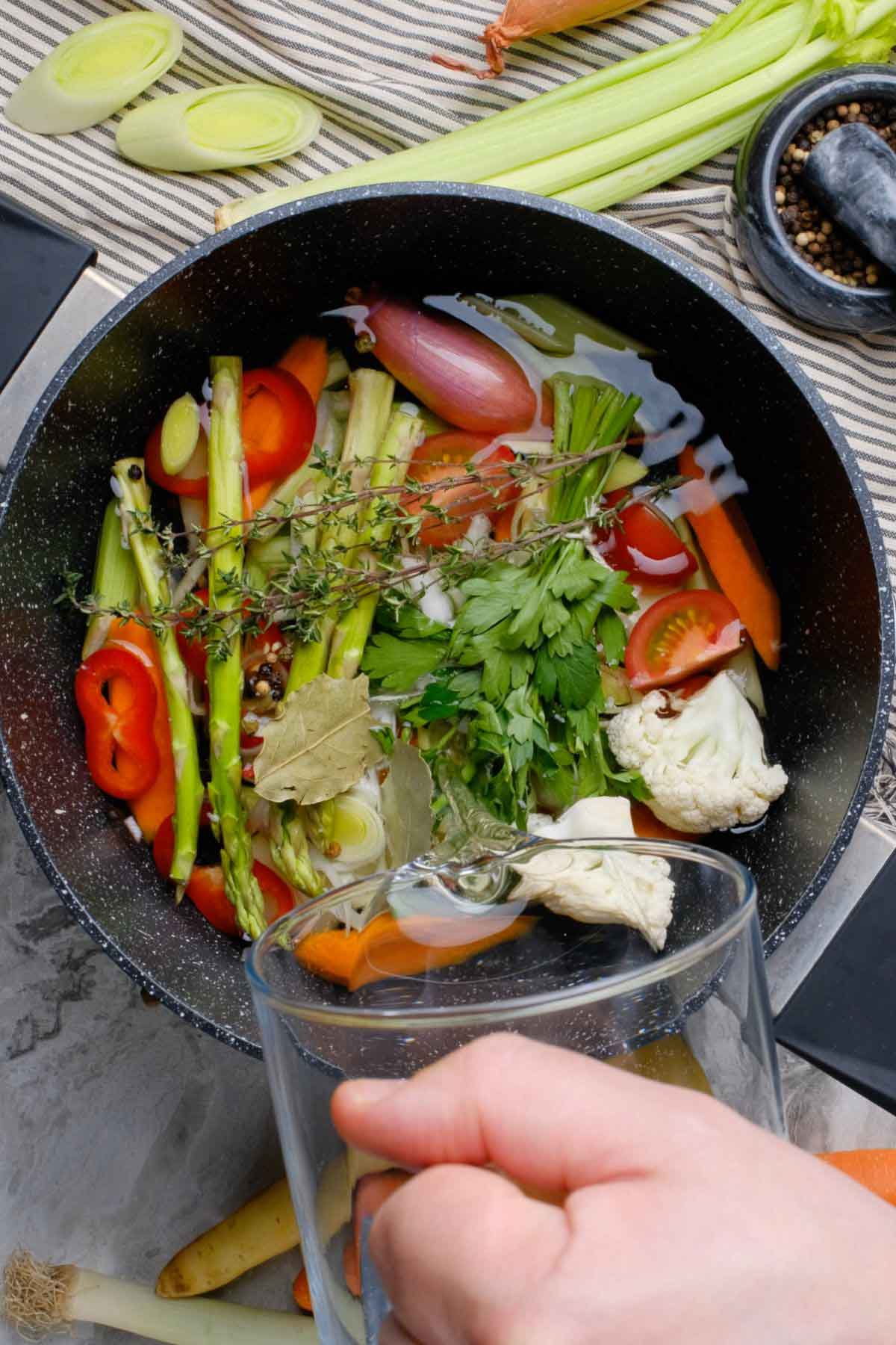 Water being poured into a pot of vegetable scraps.