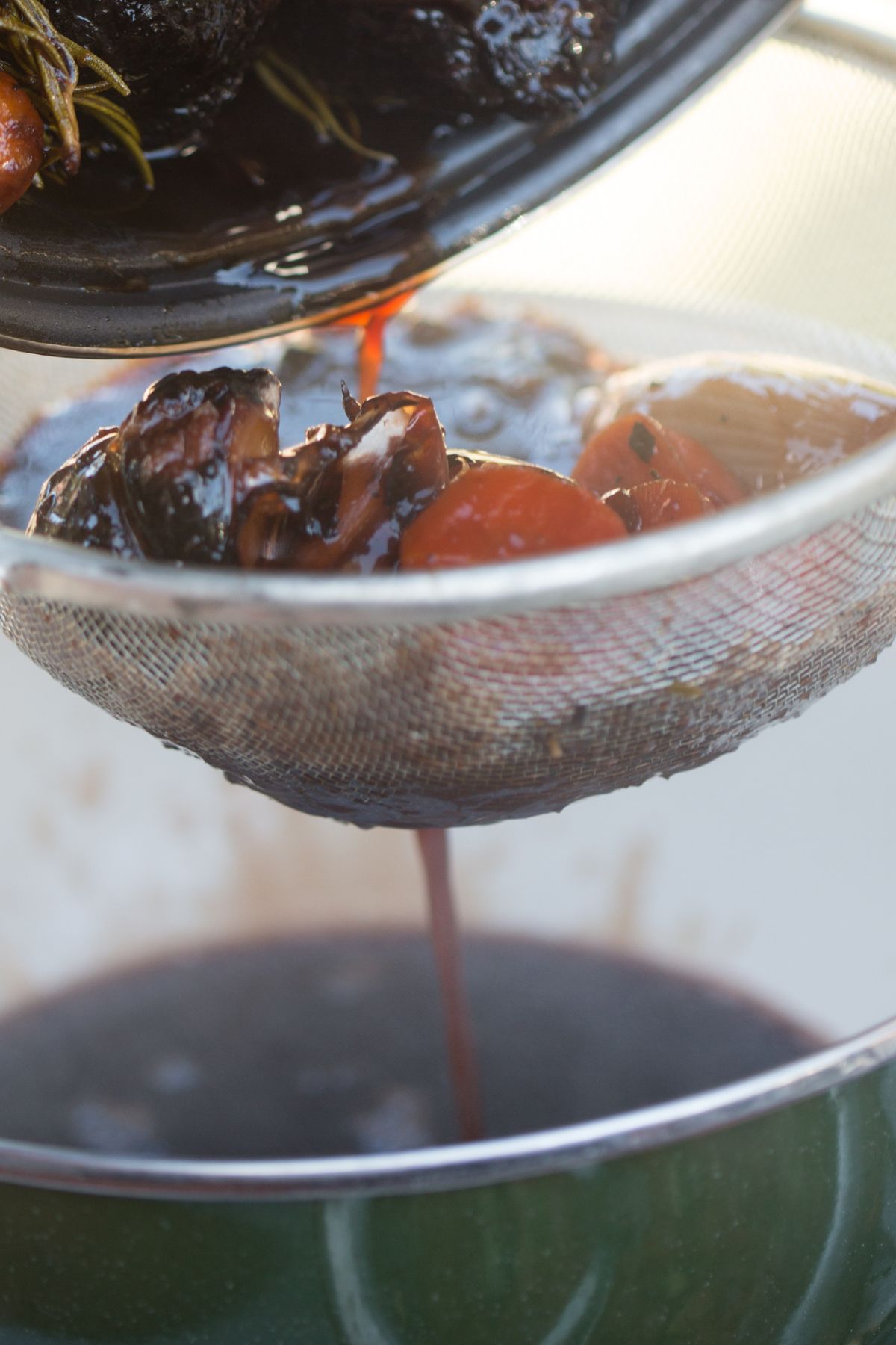 Vegan broth being strained through a fine mesh strainer.