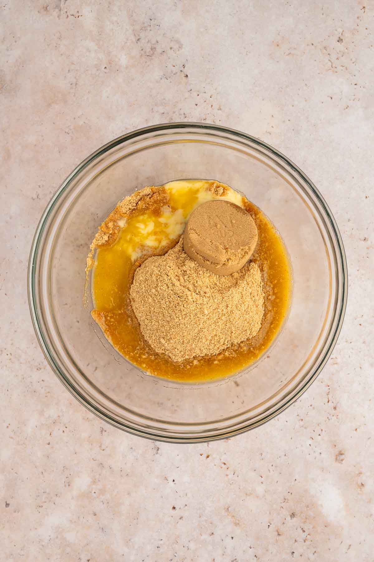The graham cracker crumbs added to a mixing bowl along with the butter and brown sugar.