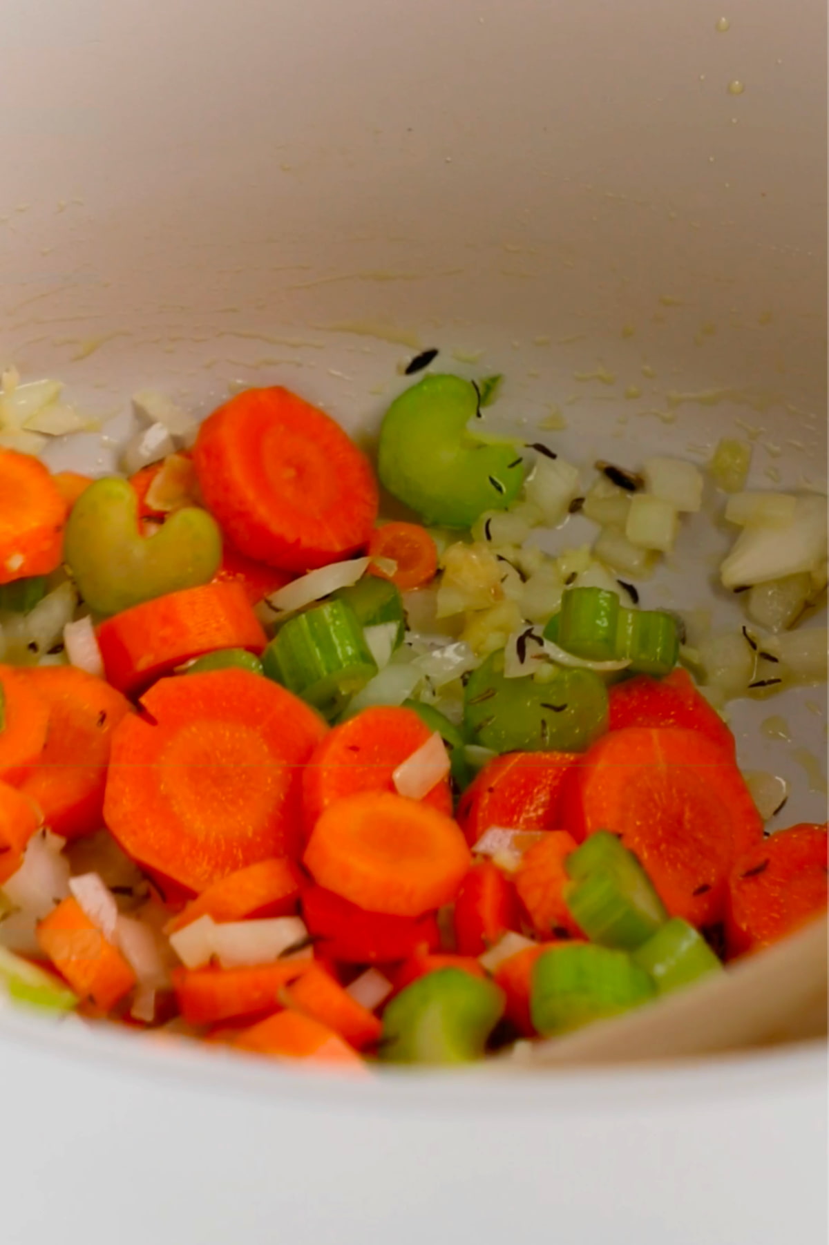 Yellow onion, carrots, and celery cooking in a large soup pot.