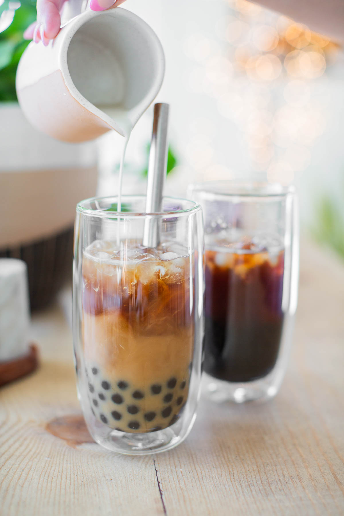 Plant-based milk being poured over boba coffee.