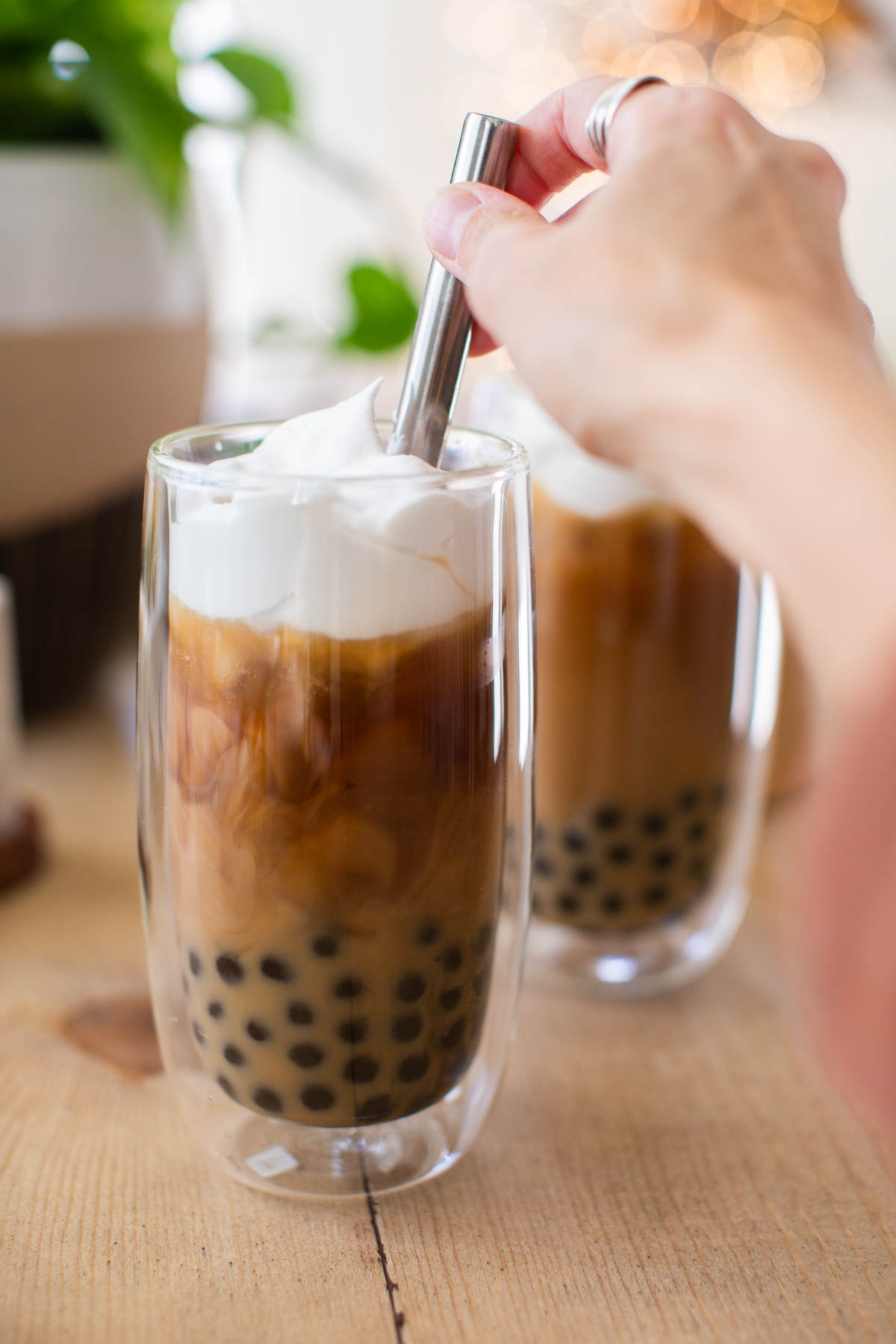 A hand stirring a glass of coffee boba.