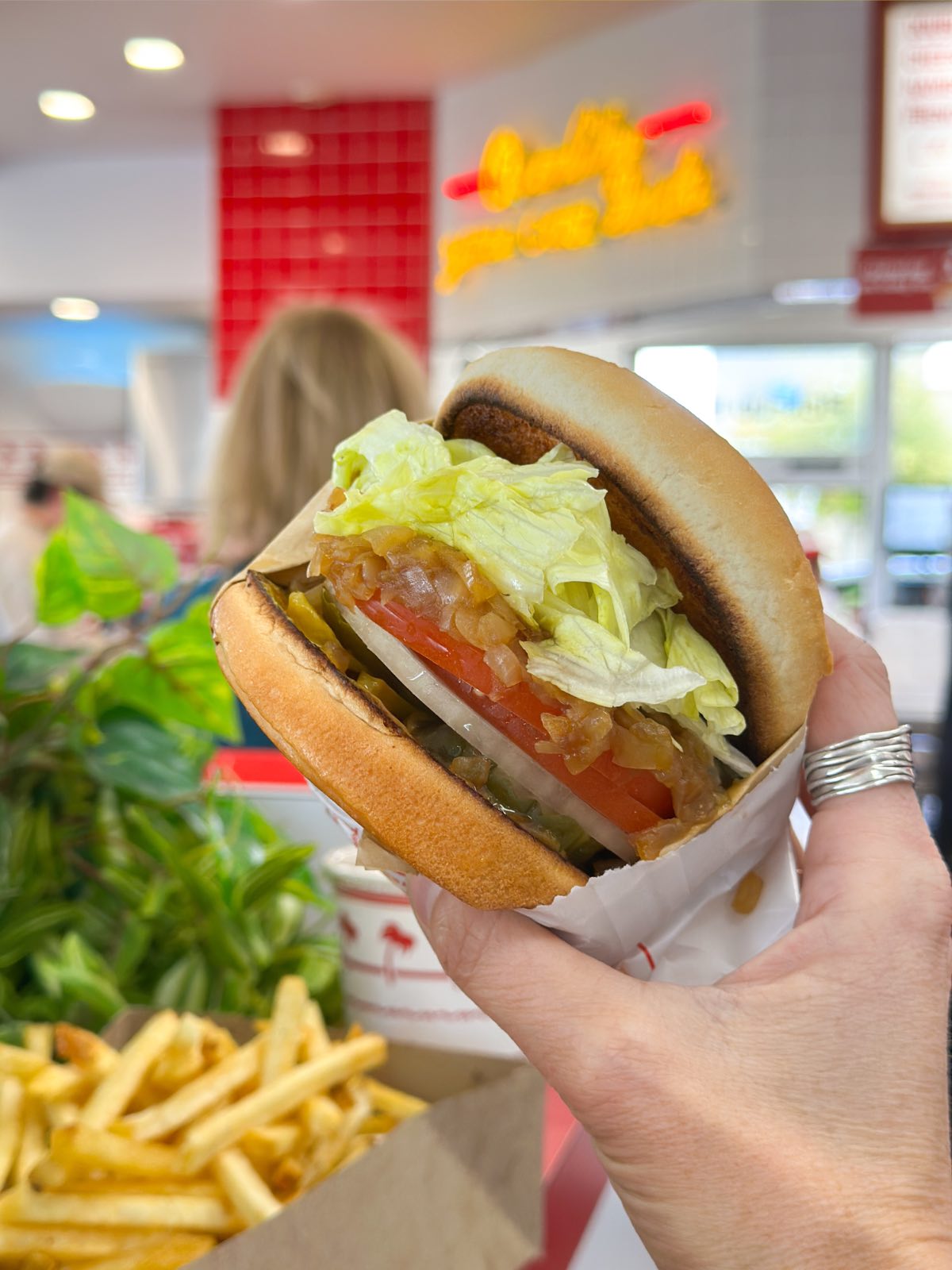 Holding out a vegan burger without a patty at In N Out loaded with fixings.