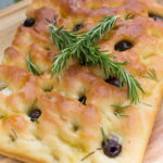 Vegan focaccia bread topped with rosemary and olives.