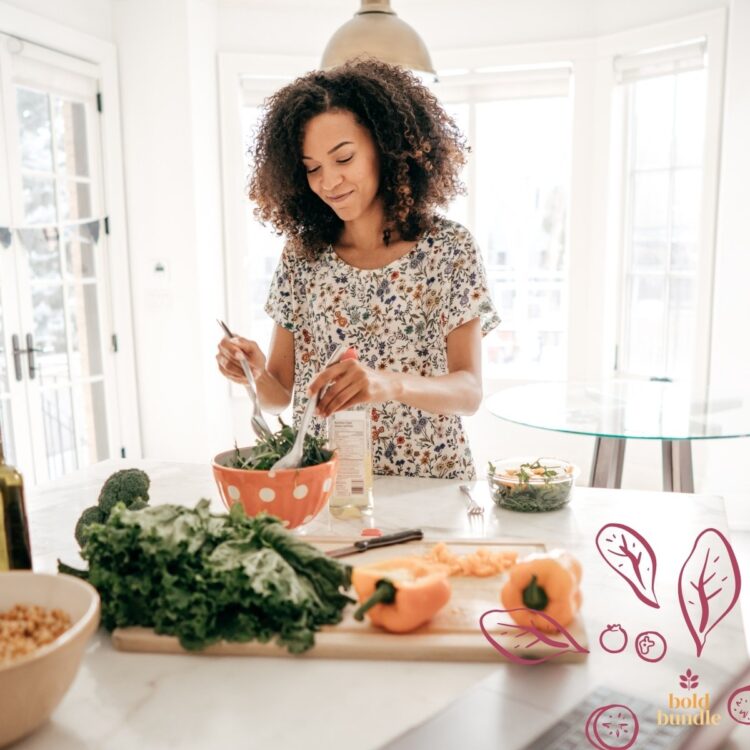 A woman in a dress mixing fresh green salad in the kitchen as part of the Bold Bundle.