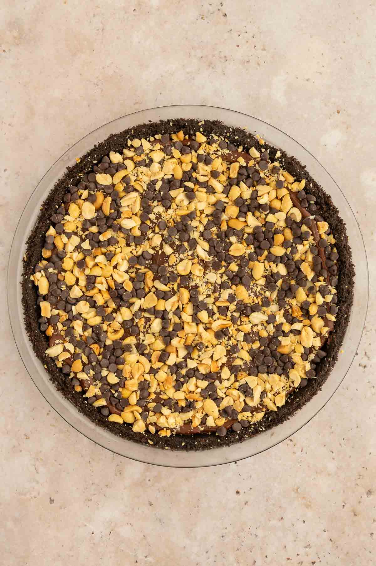 A vegan chocolate peanut butter pie with chopped nuts.