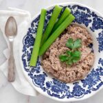 Mock chopped liver on a plate garnished with celery sticks and fresh parsley.