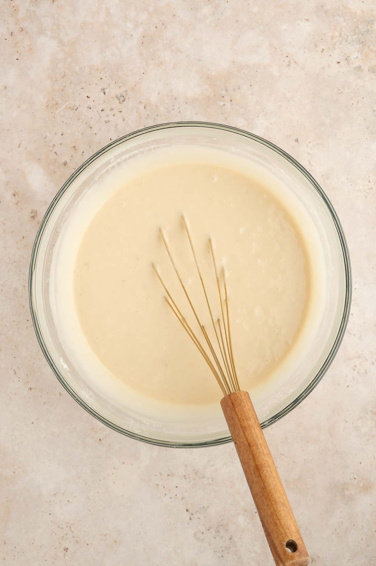 Aquafaba meringue folded into sponge cake batter in a glass bowl.