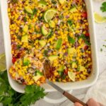 A large spatula scooping out a serving of bean and rice casserole from a serving dish.