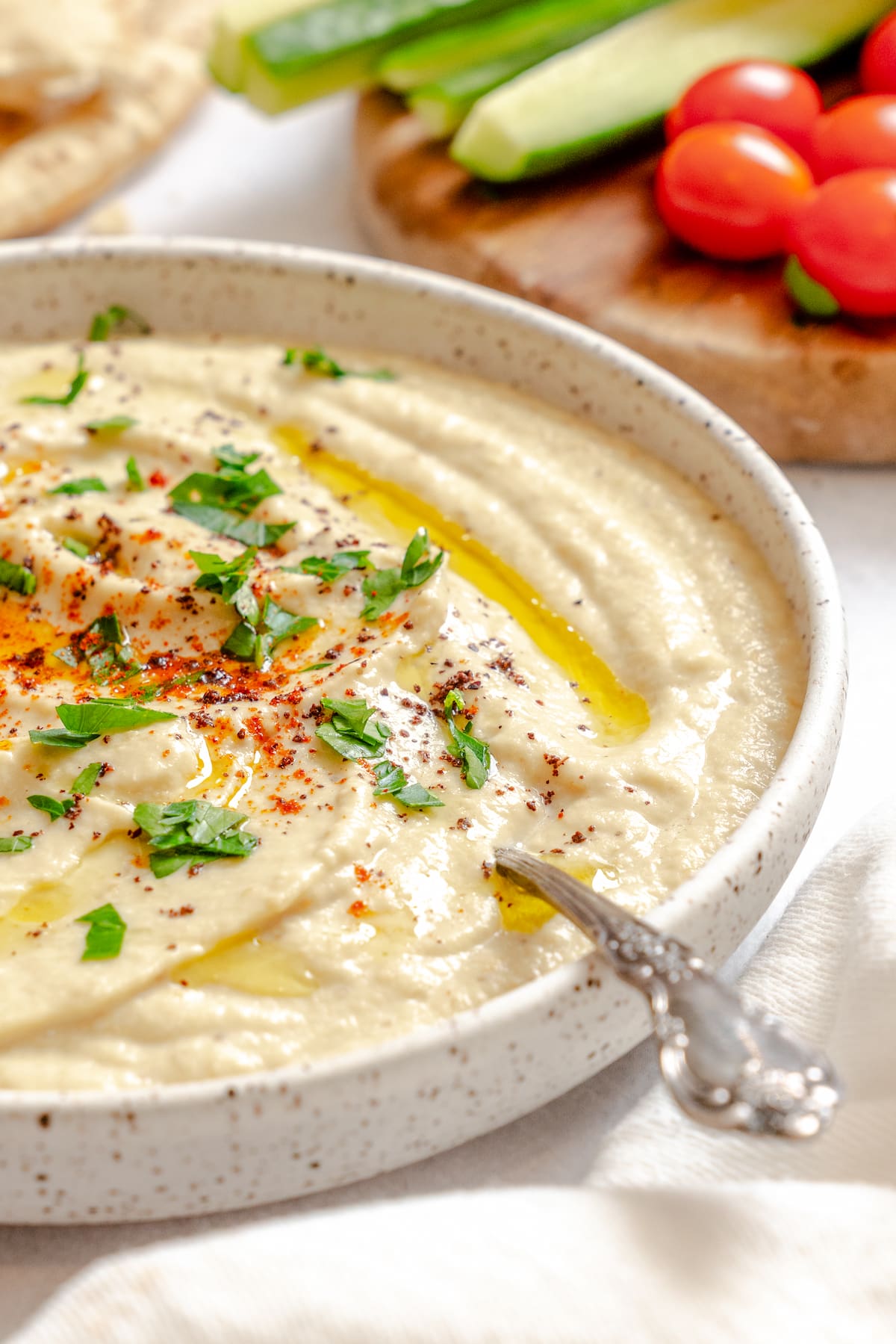 A bowl of homemade eggplant dip topped with a sprinkle of paprika, chopped parsley, and a swirl of olive oil.