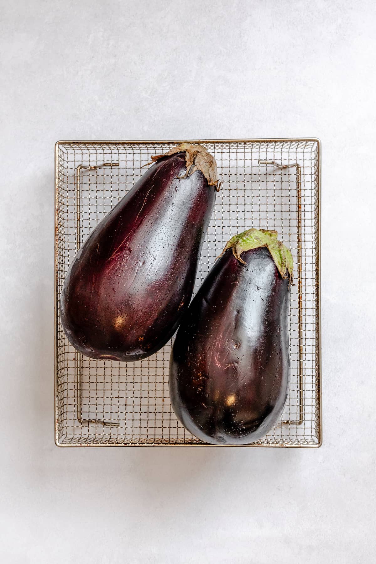 Two fresh and washed eggplants on a tray.