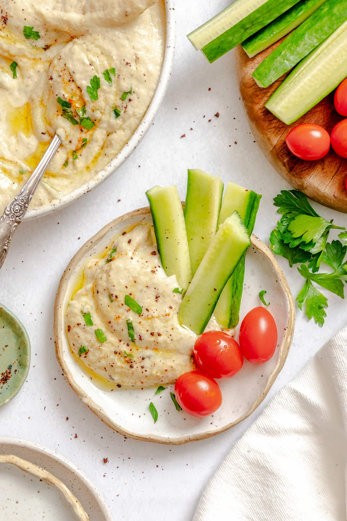 Roasted eggplant dip on a plate with a few cherry tomatoes and a few slices of cucumber.