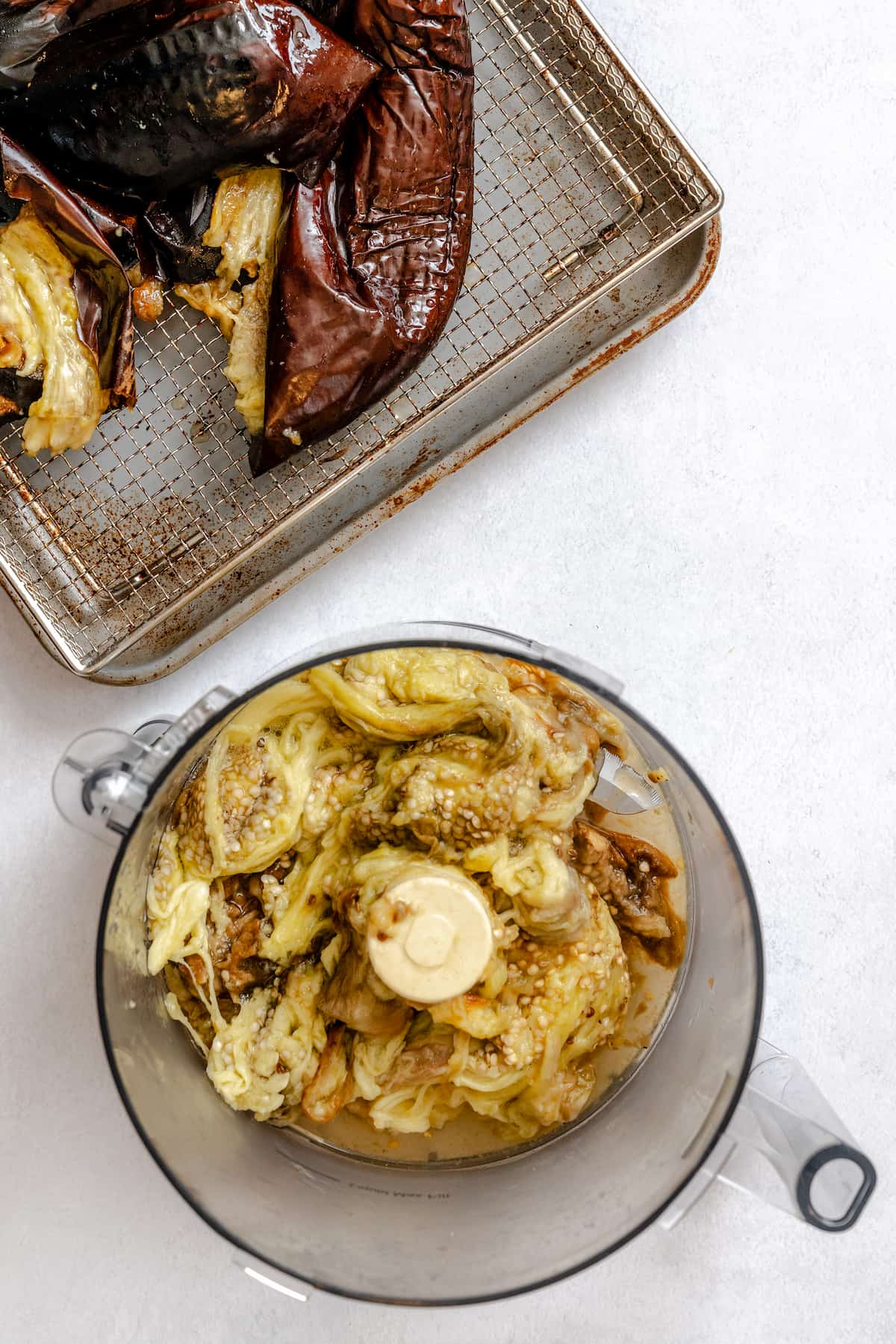 Roasted eggplants with the flesh scooped out into a food processor.