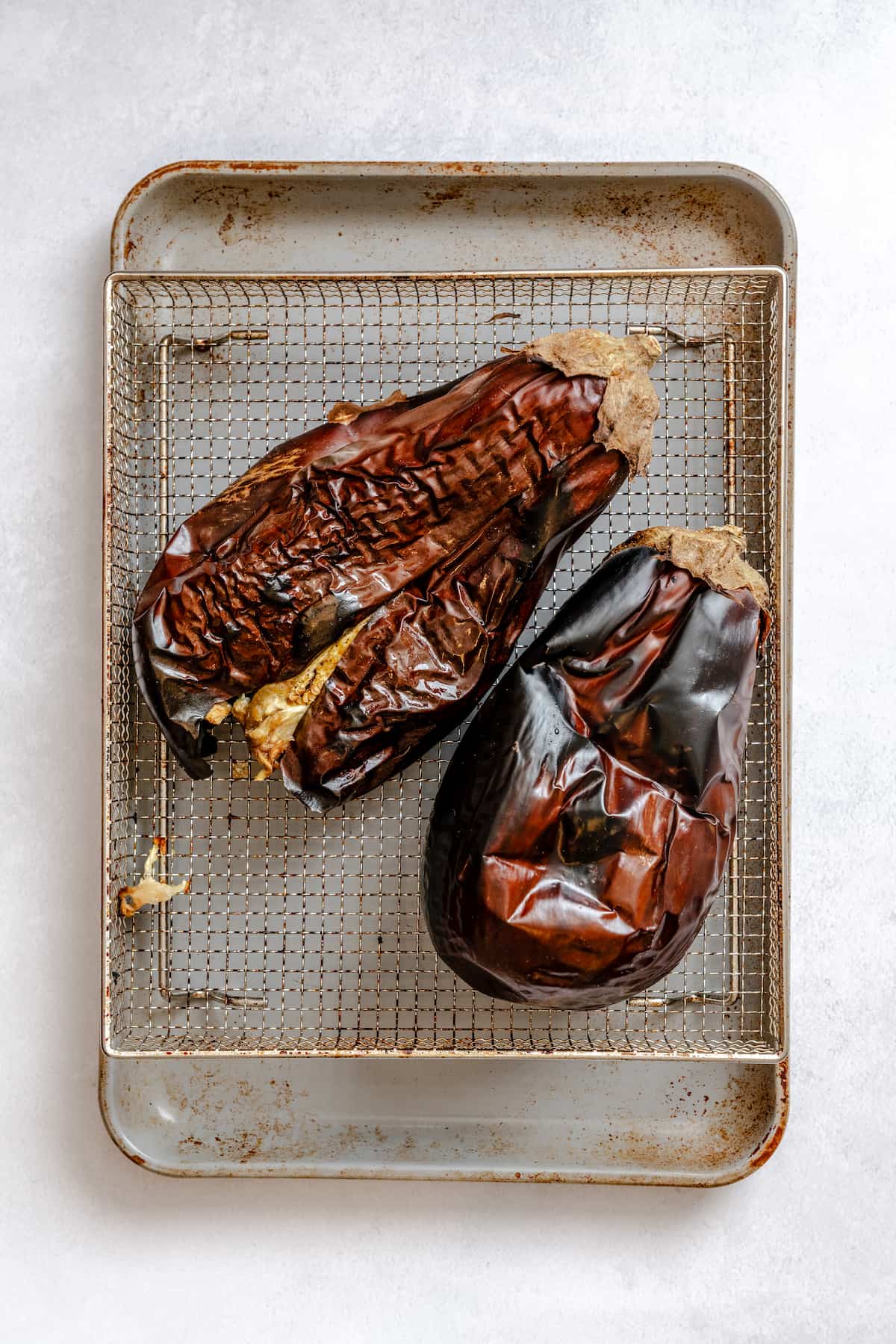 Two roasted eggplants on a tray.