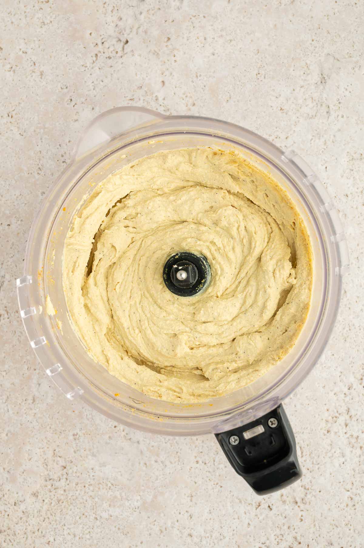 Tofu blended with nutritional yeast, salt, pepper, garlic powder, and turmeric in a food processor.