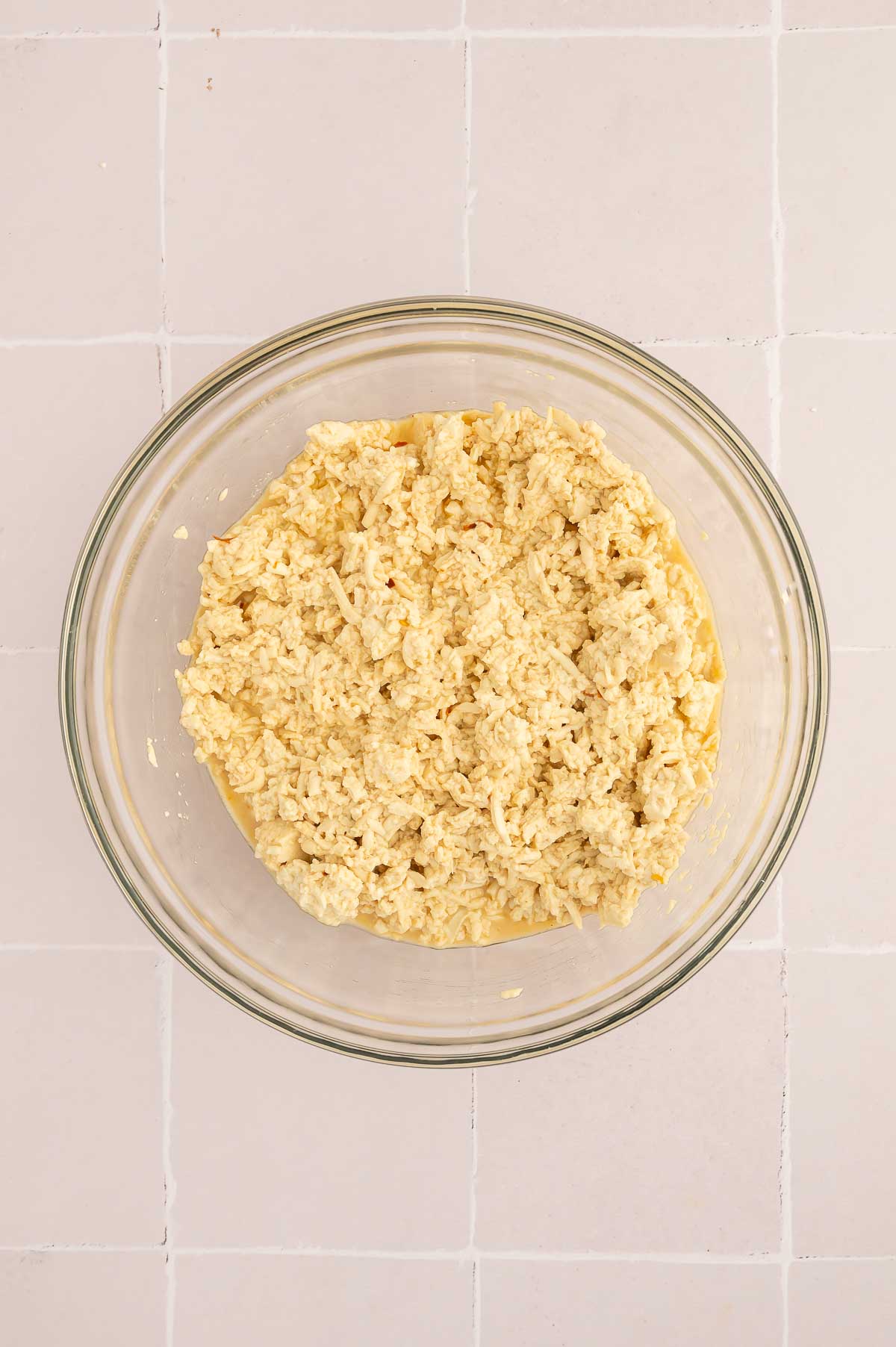 Shredded tofu in a large mixing bowl with seasonings mixed in.