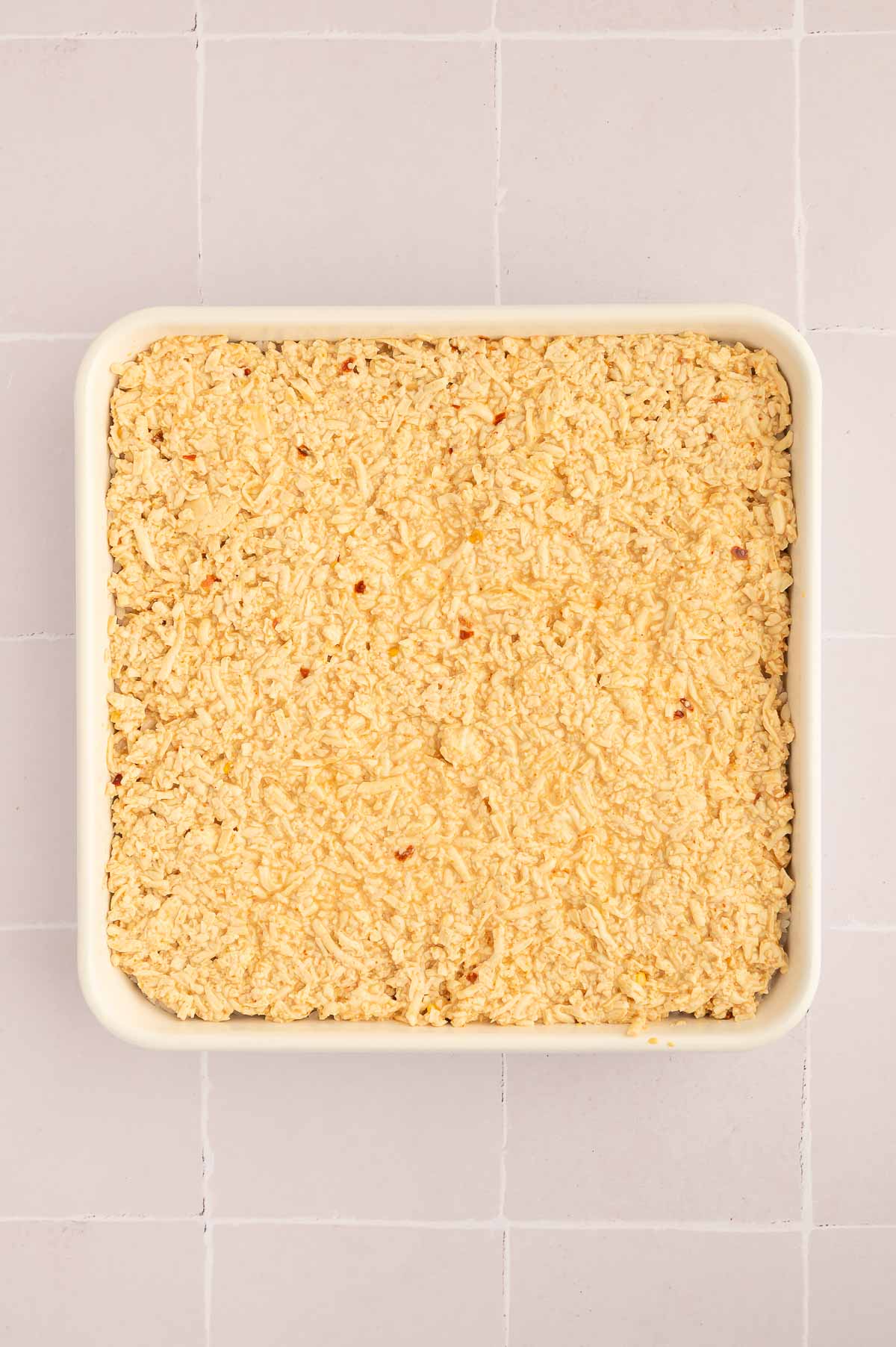 Shredded tofu vegan "crab" mixture spread evenly over a layer of sushi rice in a baking dish.