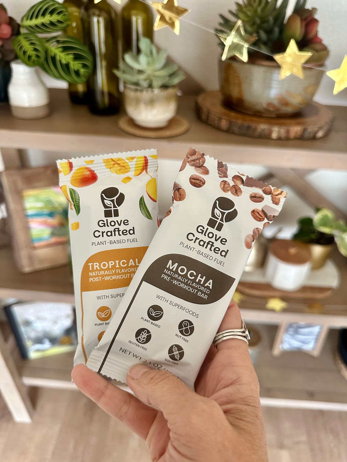 A hand holding two Glove Crafted vegan protein bars in flavors mocha and tropical.