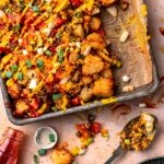 A pan with a tray of cheesy vegan tater tot casserole and a bottle of ketchup.