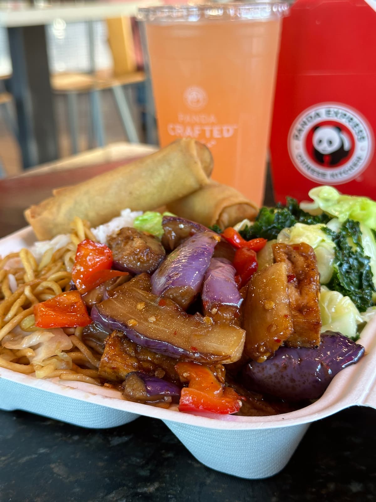 Vegan Eggplant Tofu at Panda Express next to a drink and take out box. 