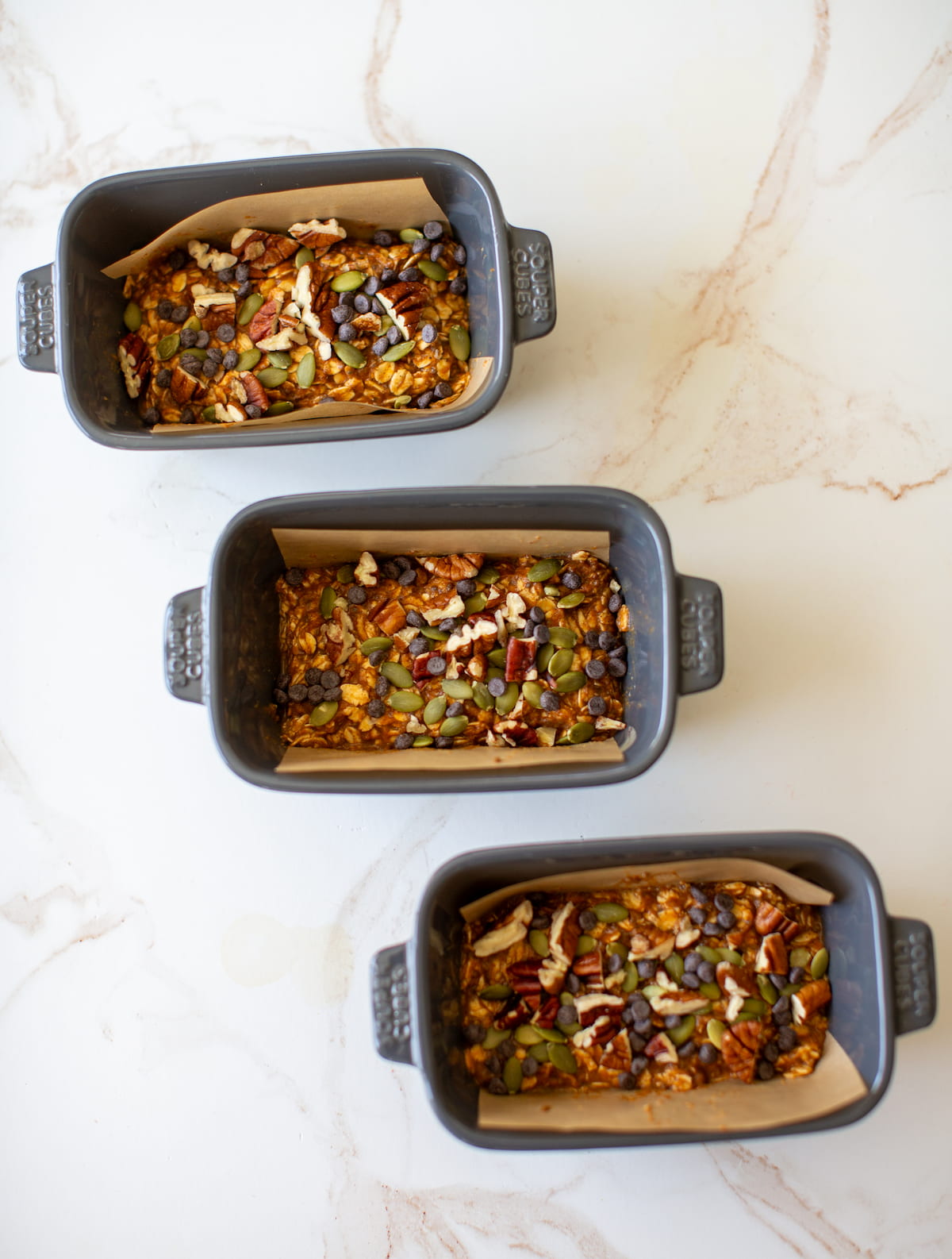 Three parchment paper-lined baking pans of pumpkin baked oatmeal.