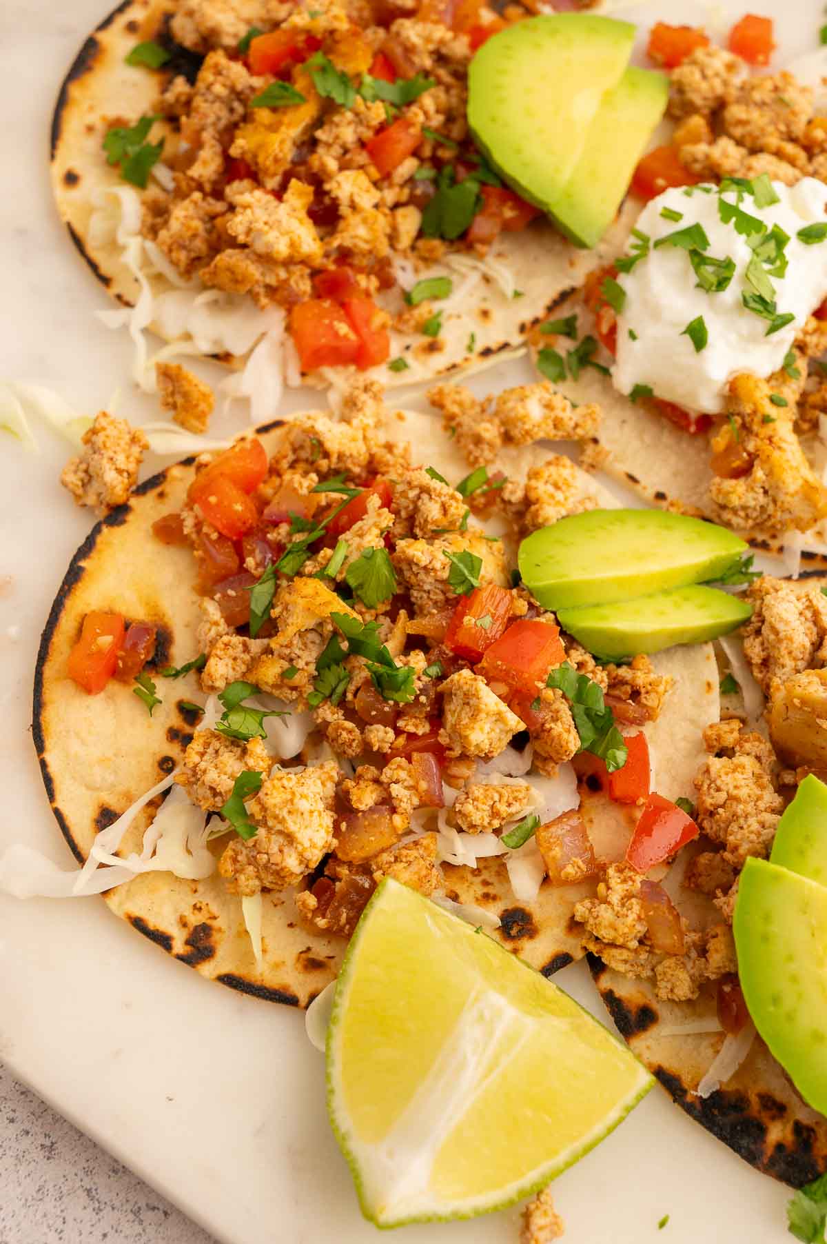 Tofu tacos topped with pico de gallo and sliced avocado.