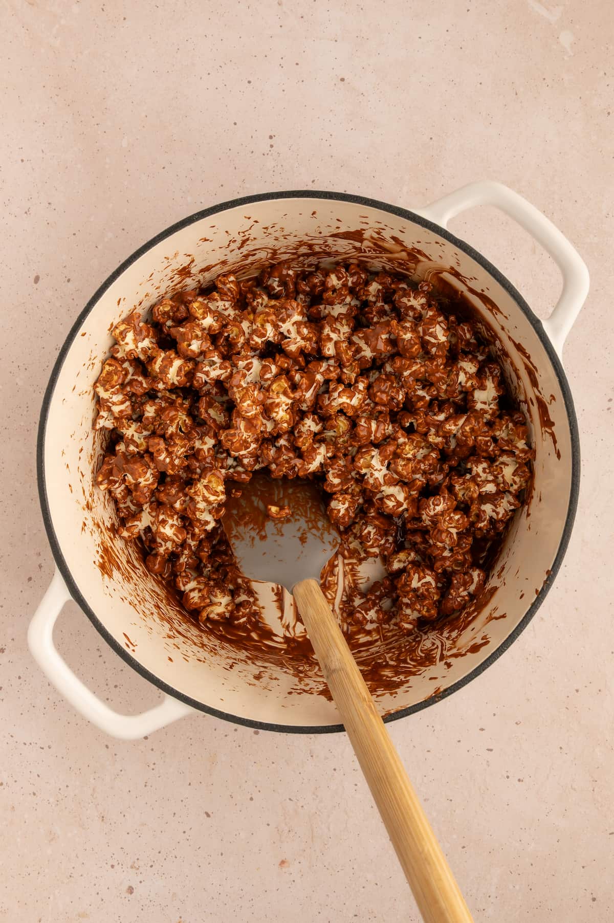 Melted peanut butter and chocolate mixed together with the popcorn in a pot.