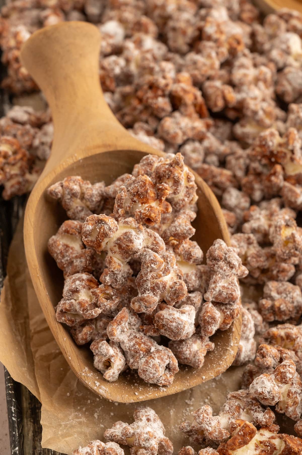 A wooden scoop holding homemade dairy-free chocolate and peanut butter popcorn.