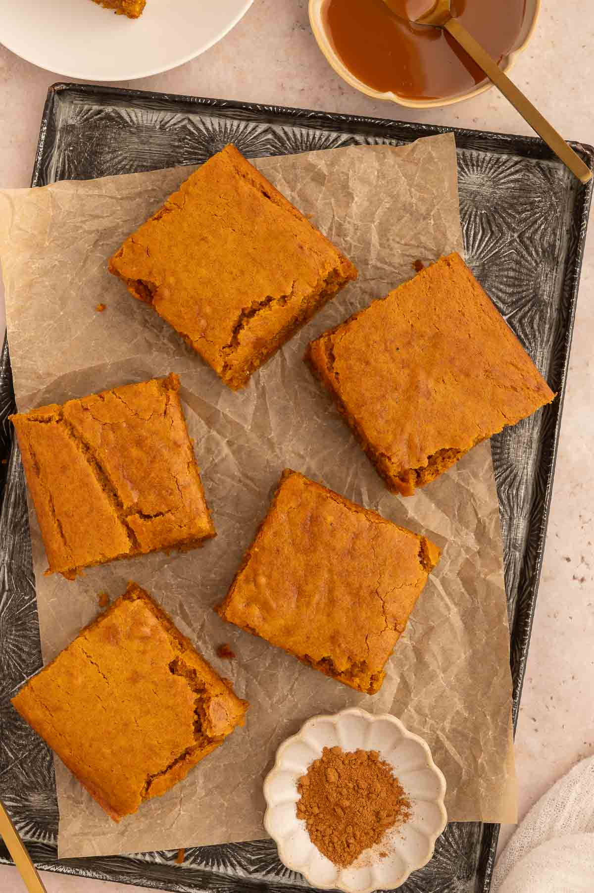 Slices of pumpkin dump cake on parchment paper, ready to be topped and served.